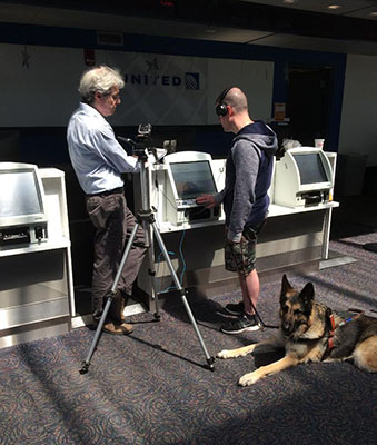 Visually impaired evaluator testing a kiosk, accompanied by his service animal.